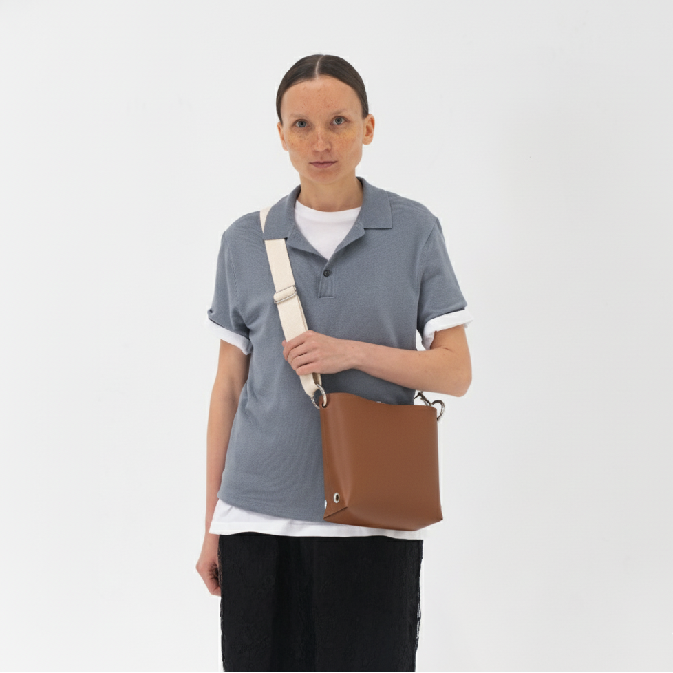 Person wearing a gray shirt with a brown bag on a white background
