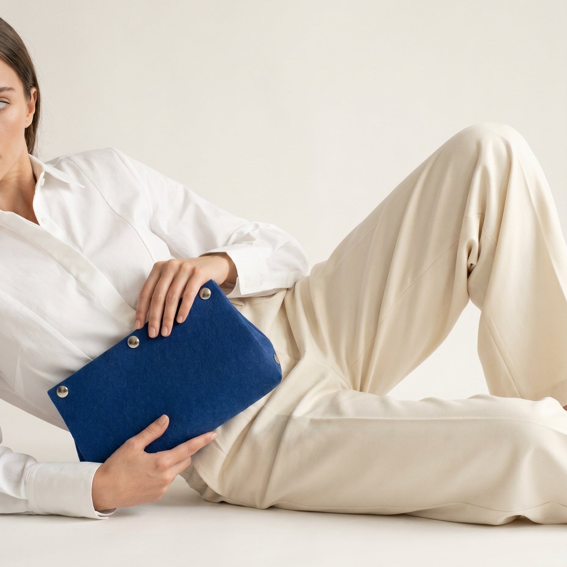 woman holding a blue clutch on a white background