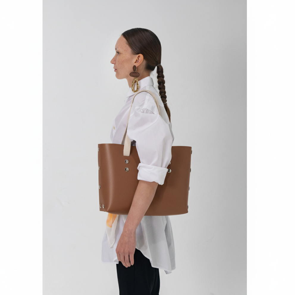 Woman holding a brown tote bag against a white background
