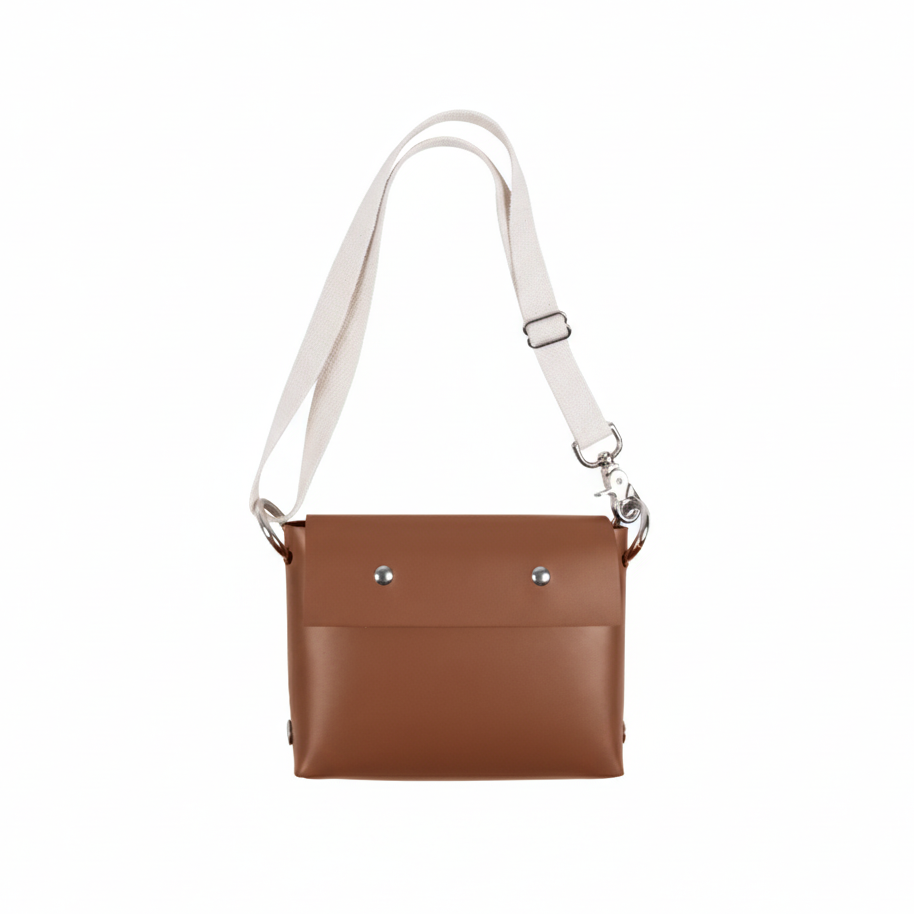 Brown leather handbag with a white strap on a white background