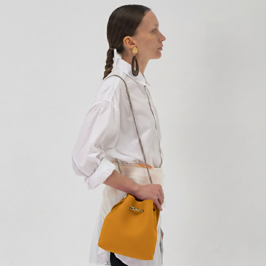 Woman holding a yellow handbag against a white background
