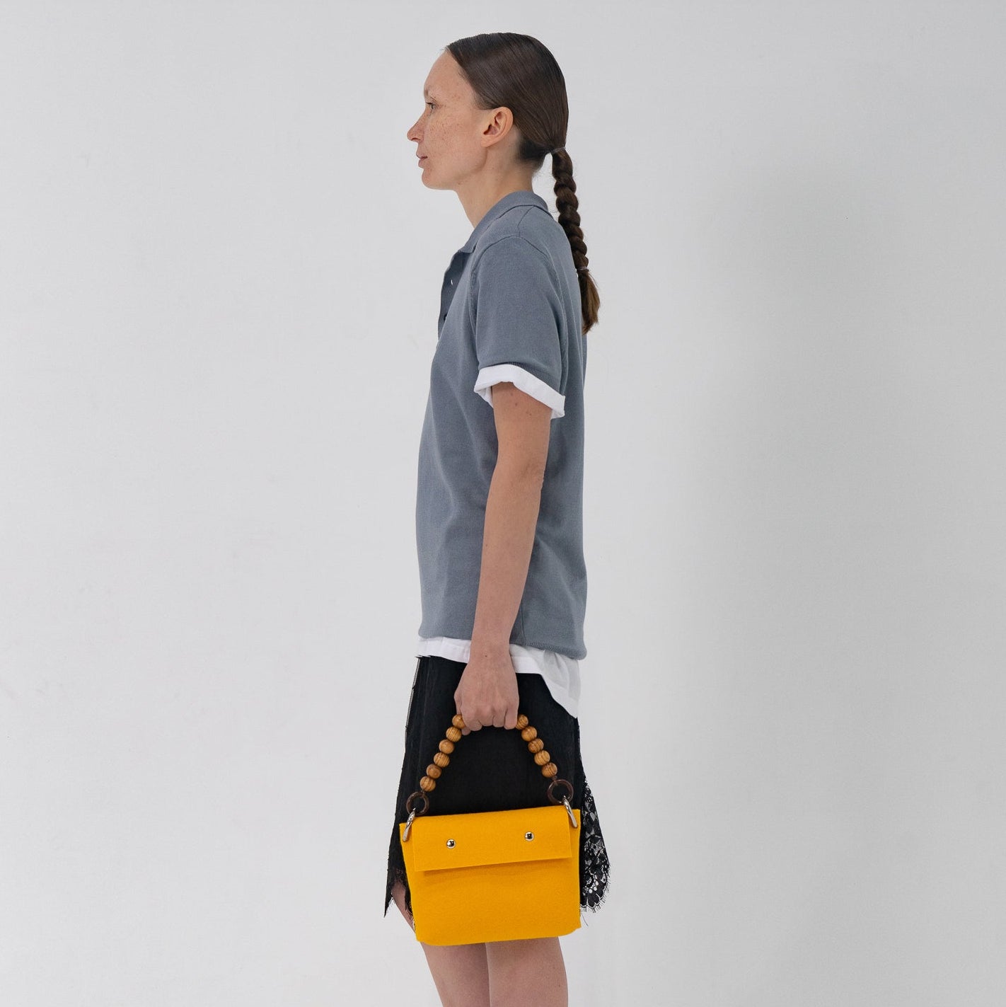 Woman holding a yellow handbag with a black top against a white background