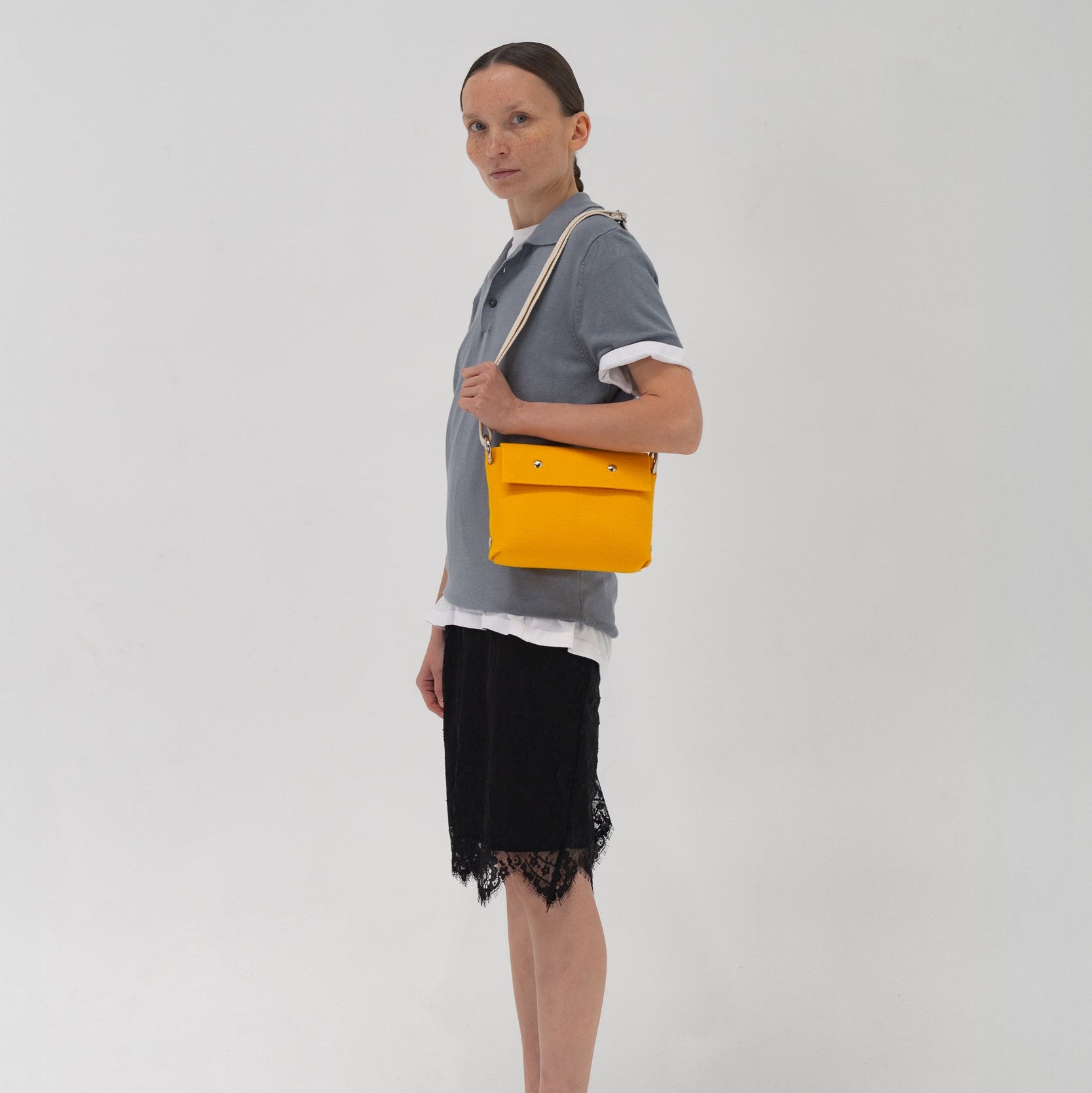 Woman holding a yellow handbag against a white background