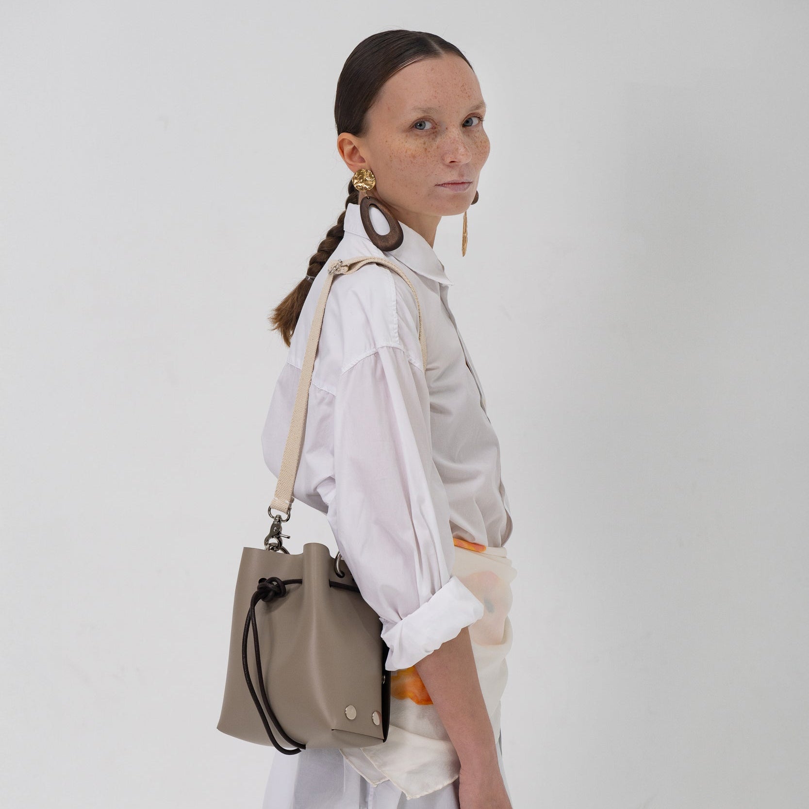 Woman holding a beige handbag against a white background