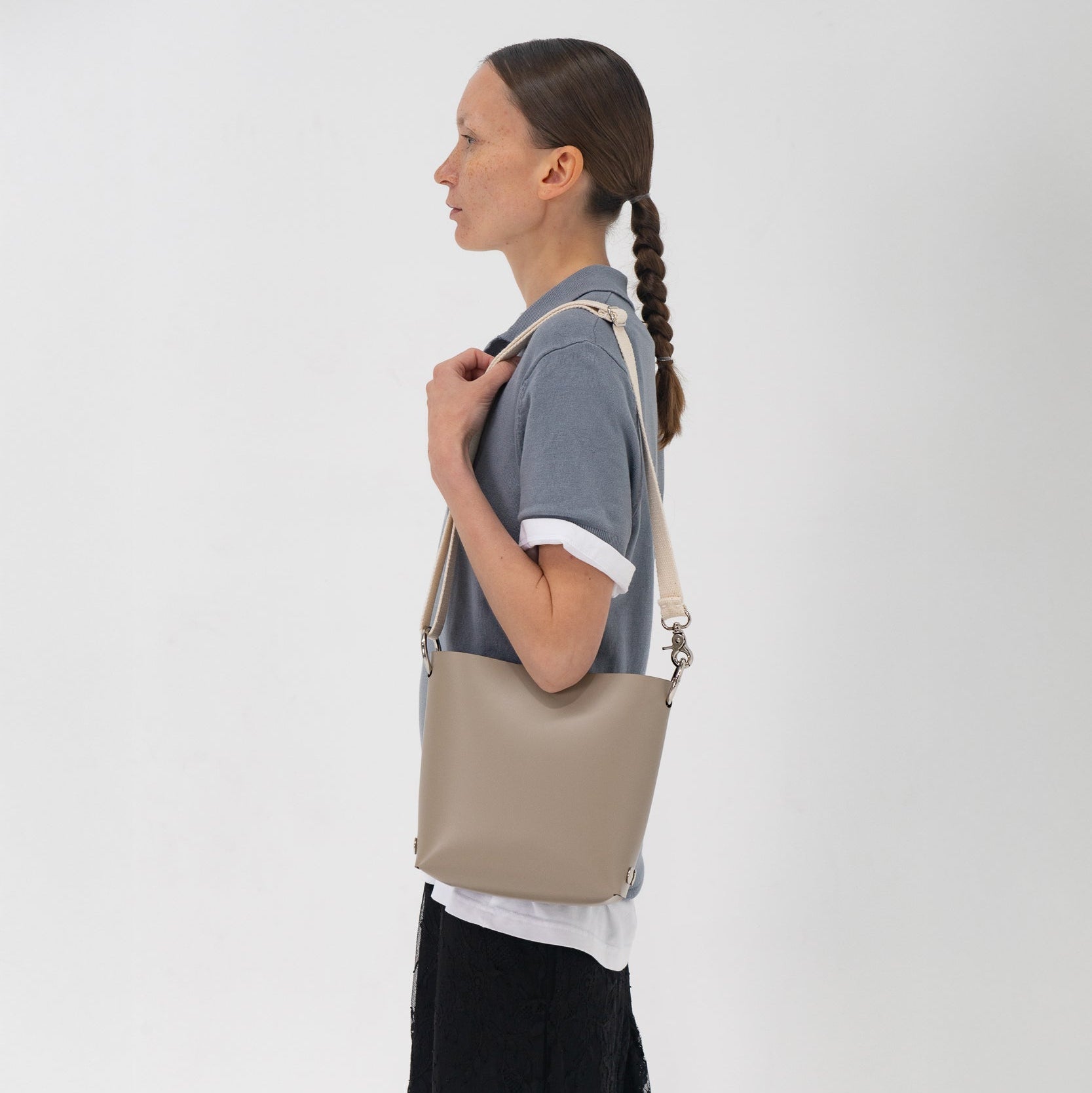 Woman carrying a beige handbag on a plain background